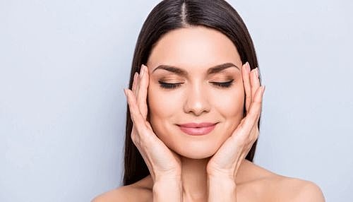 Tucson Juvederm model relaxing with hands on her face.