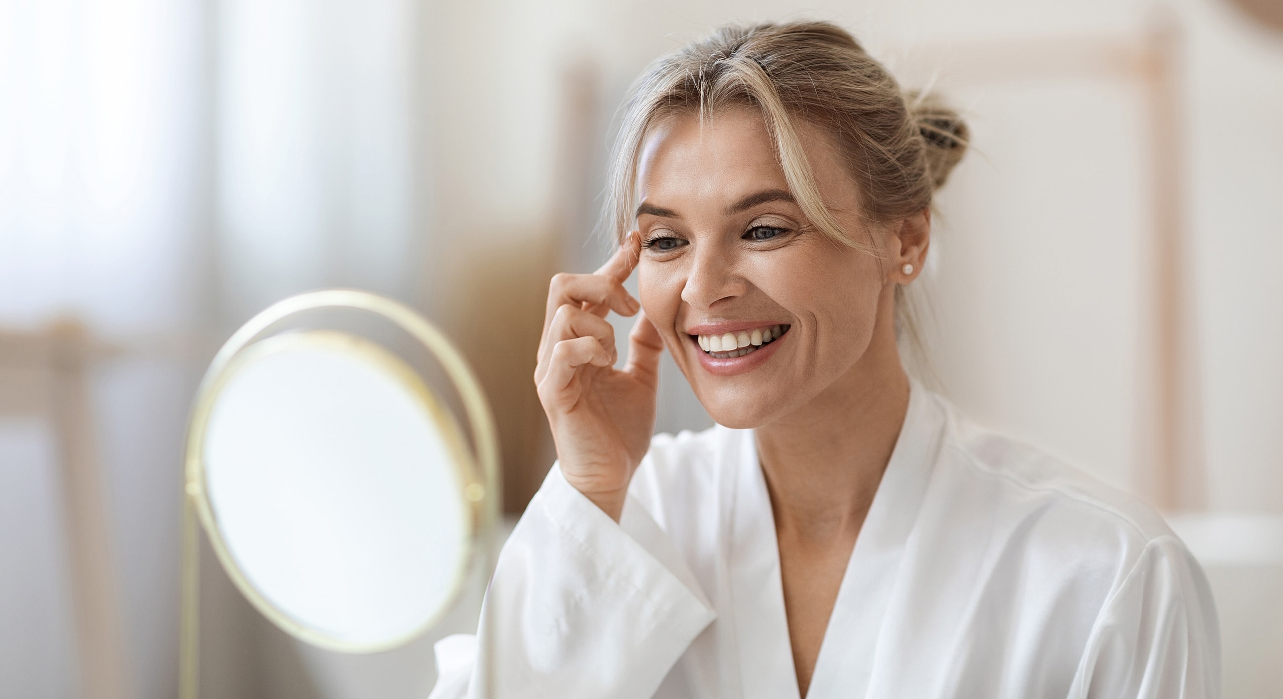 Tucson Facelift model applying skincare in front of mirror.